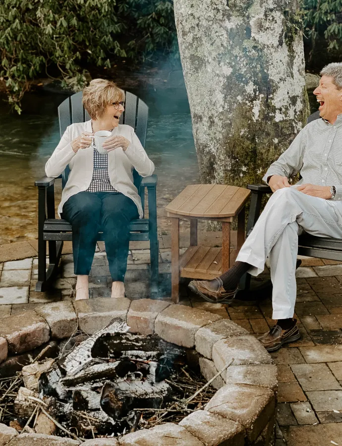 Couple on Poly Rockers by Fire Pit and Creek